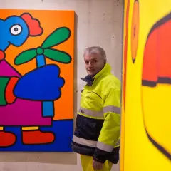 Thierry Noir, artiste emblématique du mur de Berlin, pose devant ses œuvres colorées.