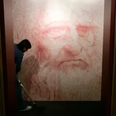 Un homme nettoie le sol devant un portrait de Léonard de Vinci, une œuvre monumentale en sanguine.