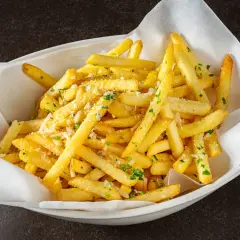 Un plat de frites dorées, parsemées de persil et de parmesan, qui donne envie d'avoir la frite !