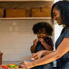 Une mère et son enfant préparent des légumes dans la cuisine. L'enfant grignote, la mère coupe. Tous les goûts sont dans la nature, même pour les plus petits !