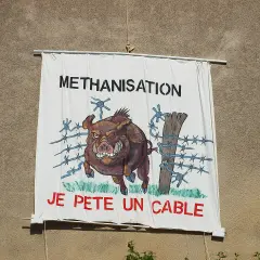 Bannière "METHANISATION" avec un sanglier en colère, prêt à péter un cable, traversant une clôture barbelée.