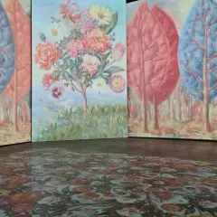 Installation d'art avec des arbres stylisés et un bouquet de fleurs, évoquant l'univers d'un peintre belge. Le sol est orné d'un motif floral projeté.