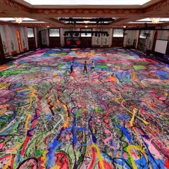 Un immense tableau, "la création du monde", recouvre le sol d'une salle. Des éclaboussures de peinture vives créent un chaos coloré, évoquant l'énergie primordiale.