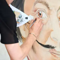 Un artiste peint le portrait de Salvador Dalí, expliquant pourquoi Salvador Dalí est connu pour son art surréaliste et son style unique.