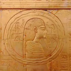 Bas-relief égyptien ancien représentant une figure dans un cercle, entourée de hiéroglyphes. Le cercle semble former un serpent qui se mord la queue, symbole d'éternité.