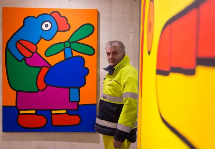 Thierry Noir, artiste emblématique du mur de Berlin, pose devant ses œuvres colorées.