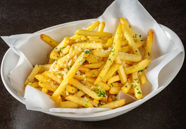 Un plat de frites dorées, parsemées de persil et de parmesan, qui donne envie d'avoir la frite !