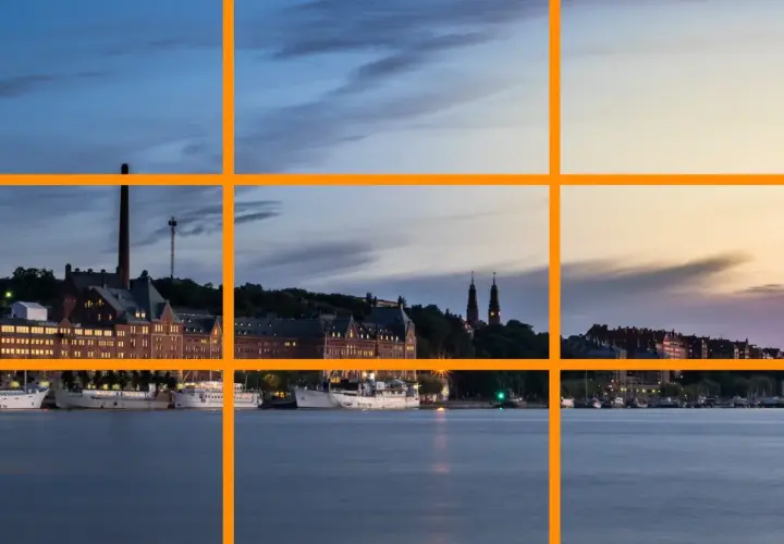 Vue d'un port au crépuscule, avec des bâtiments historiques et des bateaux. La ligne de force de la composition suit le rivage.