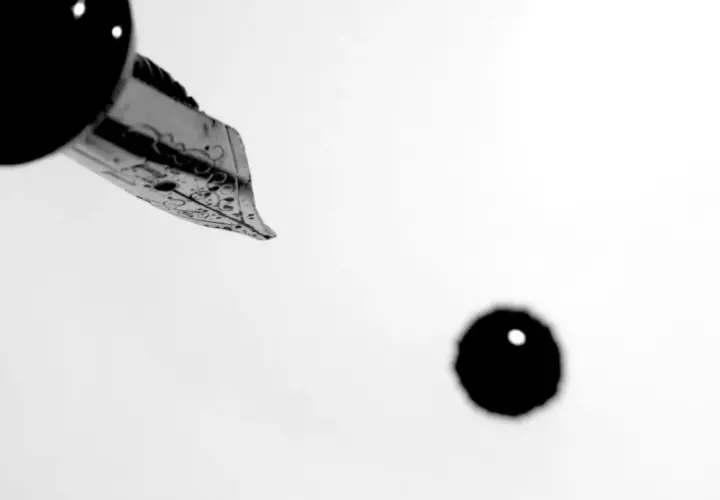 Plume d'une plume d'encre ornée, prête à écrire. Une goutte d'encre tombe, faisant se faire un sang d'encre pour le résultat.