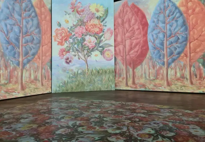 Installation d'art avec des arbres stylisés et un bouquet de fleurs, évoquant l'univers d'un peintre belge. Le sol est orné d'un motif floral projeté.