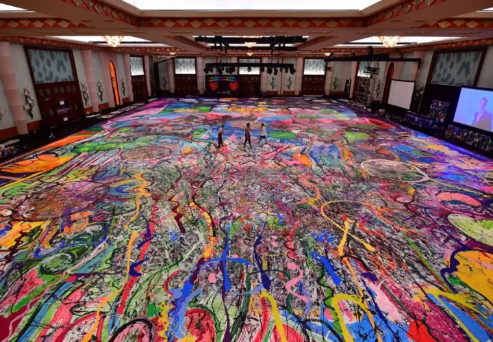 Un immense tableau, "la création du monde", recouvre le sol d'une salle. Des éclaboussures de peinture vives créent un chaos coloré, évoquant l'énergie primordiale.