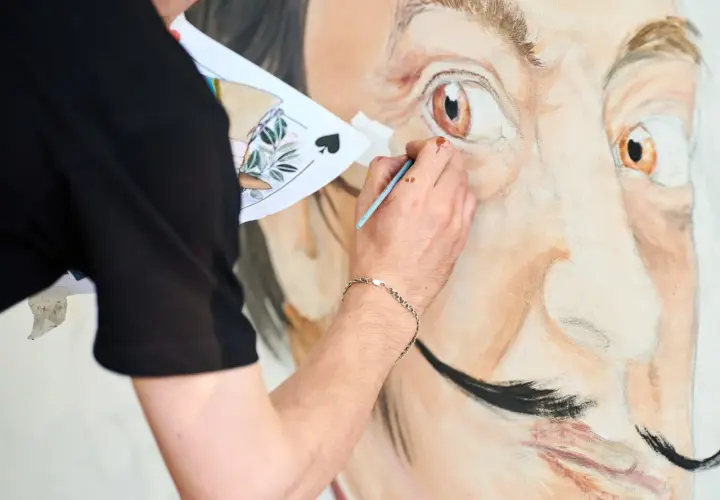 Un artiste peint le portrait de Salvador Dalí, expliquant pourquoi Salvador Dalí est connu pour son art surréaliste et son style unique.