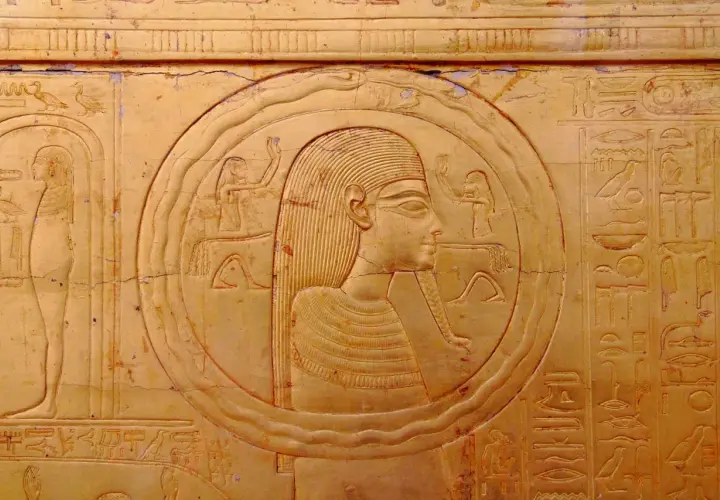 Bas-relief égyptien ancien représentant une figure dans un cercle, entourée de hiéroglyphes. Le cercle semble former un serpent qui se mord la queue, symbole d'éternité.