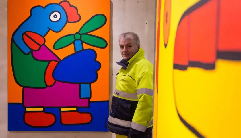 Thierry Noir, artiste emblématique du mur de Berlin, pose devant ses œuvres colorées.