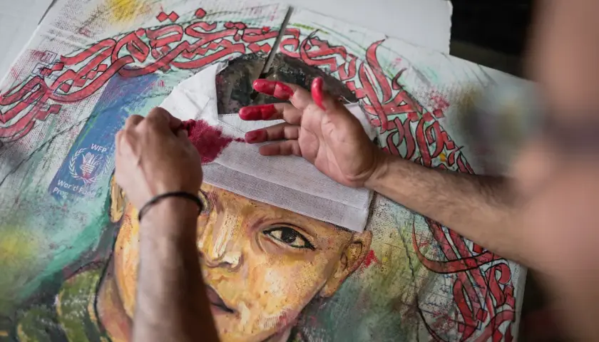 Mains peintes en rouge travaillant sur un portrait, avec des calligraphies arabes rouges vives. Le drapé dans l'art prend une nouvelle dimension.