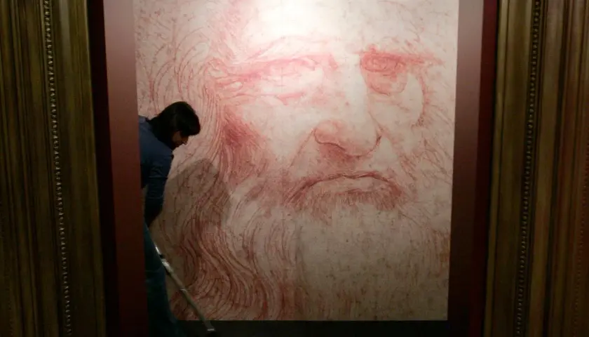 Un homme nettoie le sol devant un portrait de Léonard de Vinci, une œuvre monumentale en sanguine.