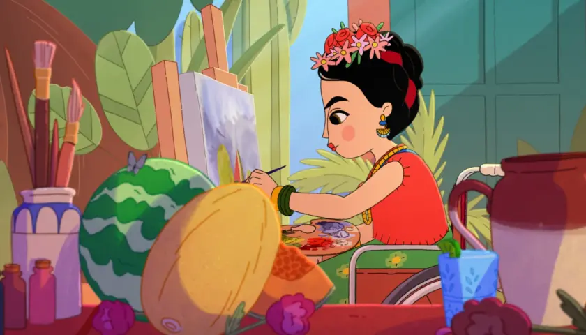 Frida Kahlo jeune, assise dans son fauteuil, peint un tableau coloré entourée de fruits et de fleurs.