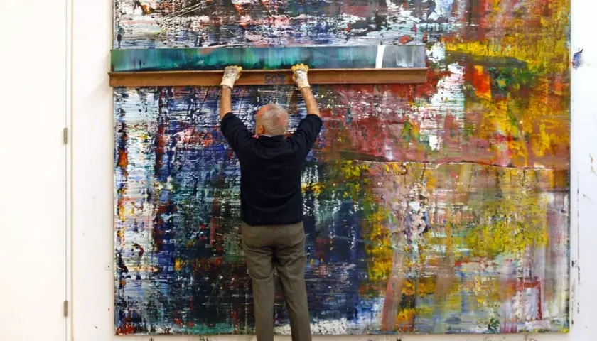 Gerhard Richter utilise une raclette sur une toile abstraite aux couleurs vives.