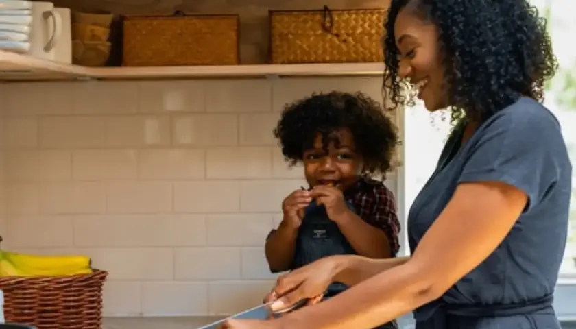 Une mère et son enfant préparent des légumes dans la cuisine. L'enfant grignote, la mère coupe. Tous les goûts sont dans la nature, même pour les plus petits !