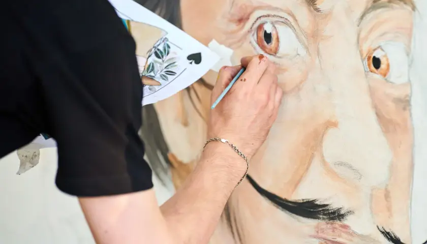 Un artiste peint le portrait de Salvador Dalí, expliquant pourquoi Salvador Dalí est connu pour son art surréaliste et son style unique.