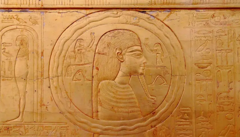 Bas-relief égyptien ancien représentant une figure dans un cercle, entourée de hiéroglyphes. Le cercle semble former un serpent qui se mord la queue, symbole d'éternité.