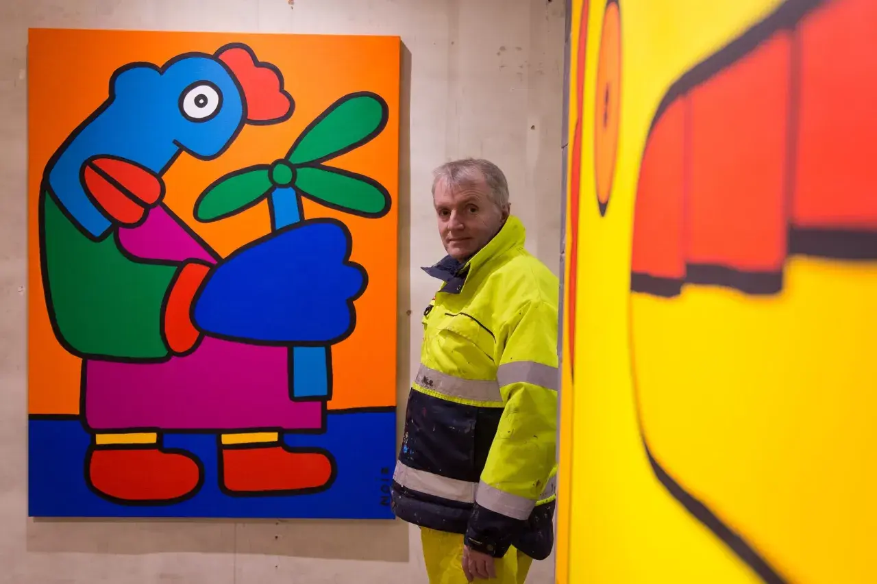 Thierry Noir, artiste emblématique du mur de Berlin, pose devant ses œuvres colorées.