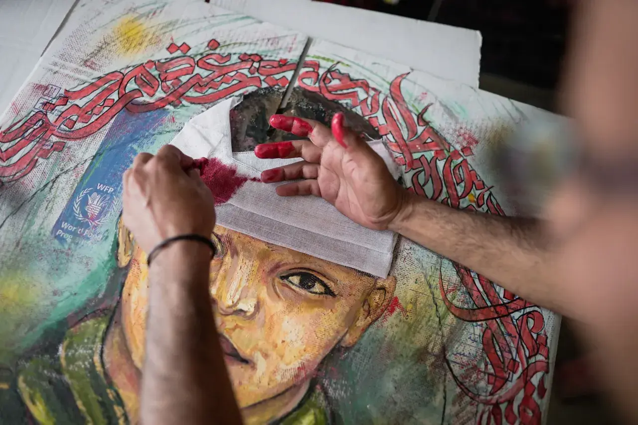 Mains peintes en rouge travaillant sur un portrait, avec des calligraphies arabes rouges vives. Le drapé dans l'art prend une nouvelle dimension.
