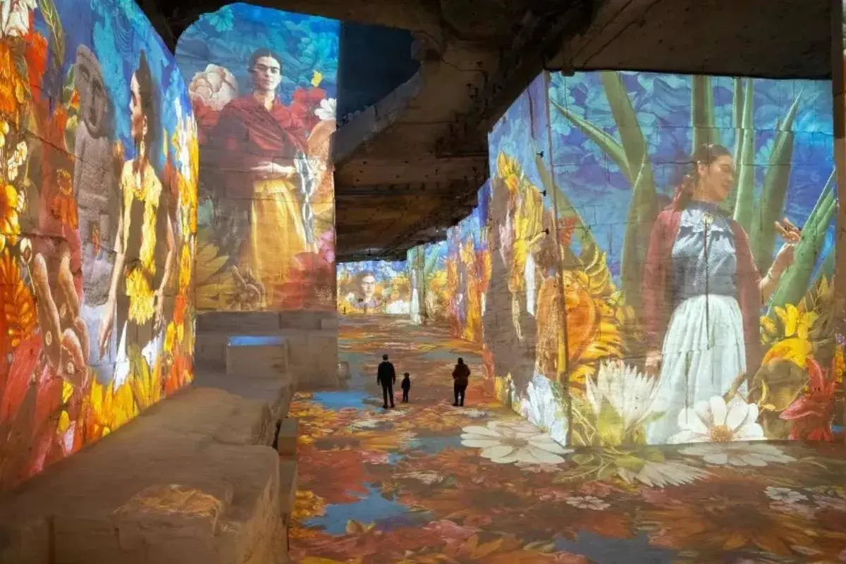 Immersion dans un univers floral et coloré, où les portraits de Frida Kahlo se mêlent à un **plein vide** d'art projeté sur les murs et le sol.