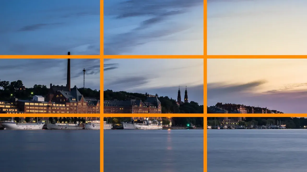 Vue d'un port au crépuscule, avec des bâtiments historiques et des bateaux. La ligne de force de la composition suit le rivage.