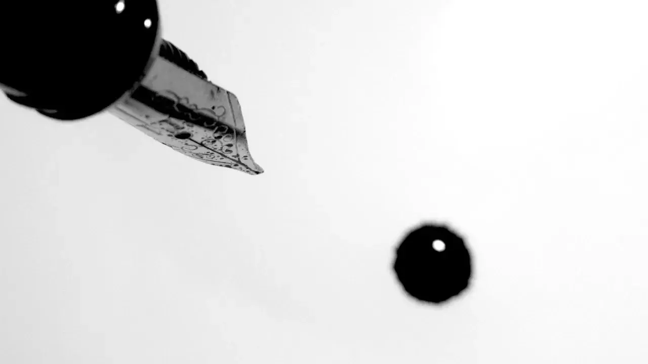 Plume d'une plume d'encre ornée, prête à écrire. Une goutte d'encre tombe, faisant se faire un sang d'encre pour le résultat.