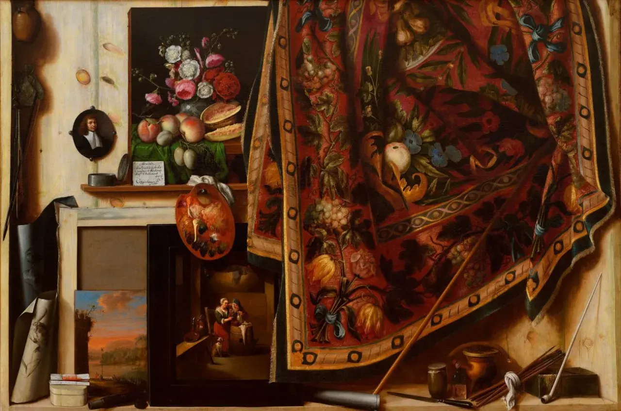 Un célèbre tableau trompe l'oeil présente un atelier d'artiste avec des fruits, des fleurs, une palette, des toiles et un tapis orné.