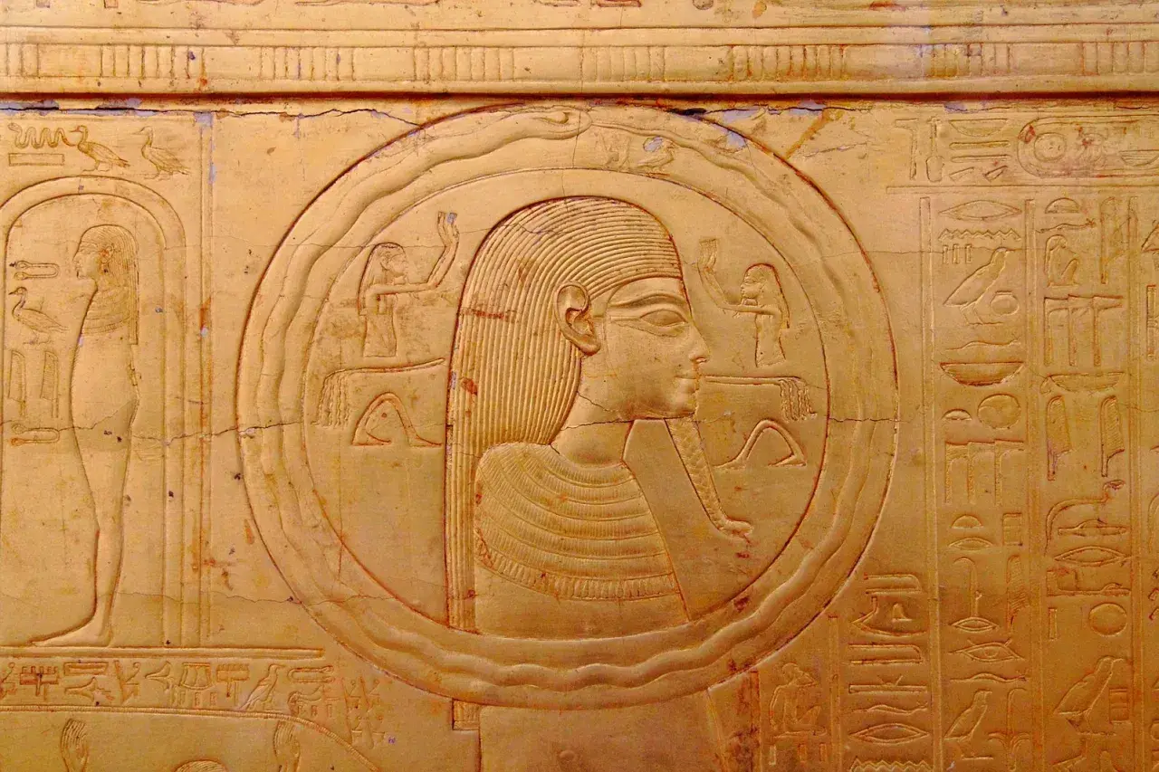 Bas-relief égyptien ancien représentant une figure dans un cercle, entourée de hiéroglyphes. Le cercle semble former un serpent qui se mord la queue, symbole d'éternité.