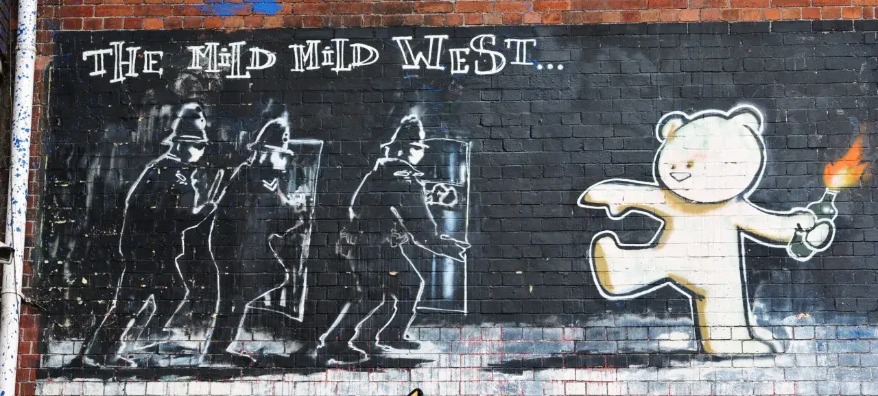 Street art connu Banksy : un ours en peluche armé d'un cocktail Molotov fait face à des policiers anti-émeute.