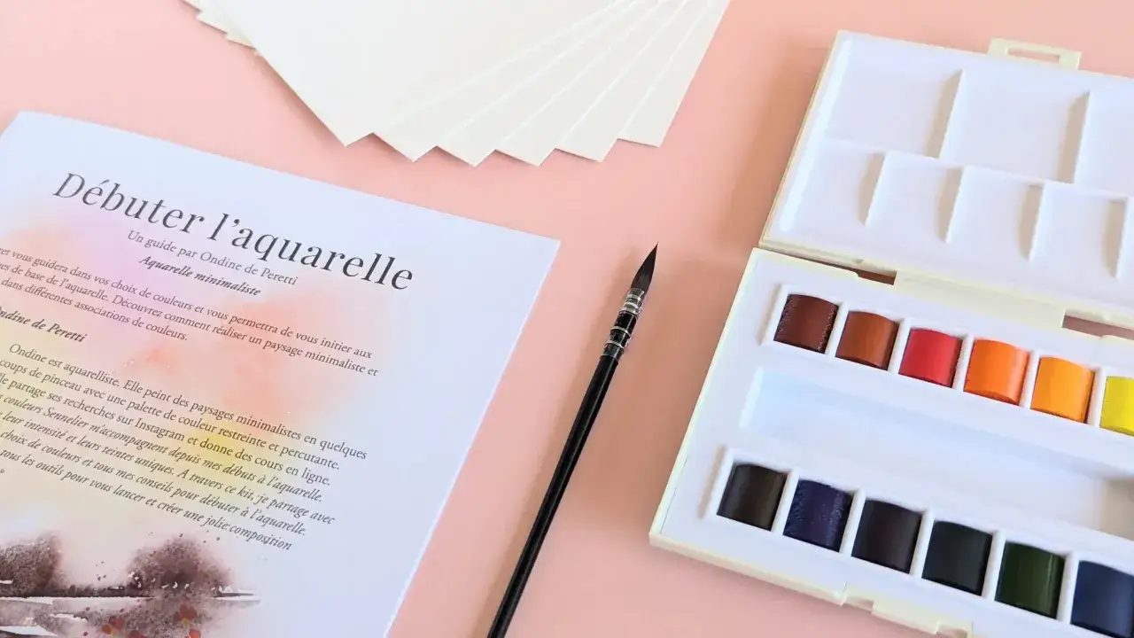 Un guide pour débuter l'aquarelle, avec une palette de couleurs vives et un pinceau. Parfait pour comprendre ce qu'est l'aquarelle.