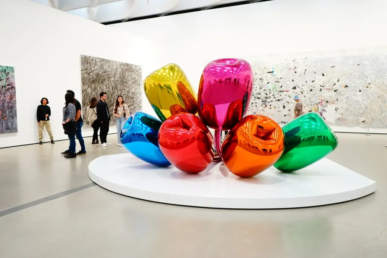 Sculptures pop art colorées, bleues, rouges, oranges, jaunes, roses et vertes, ressemblant à des ballons, dans une galerie d'art.